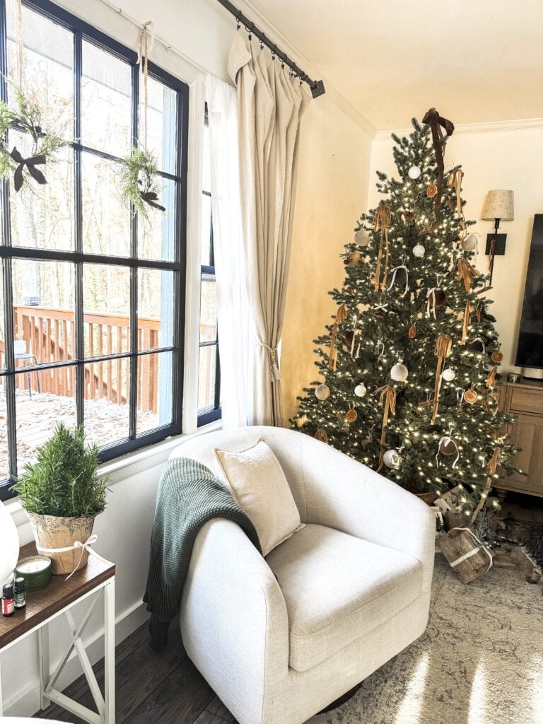 Decorated Christmas tree with warm lights and ornaments in cozy living room setting.