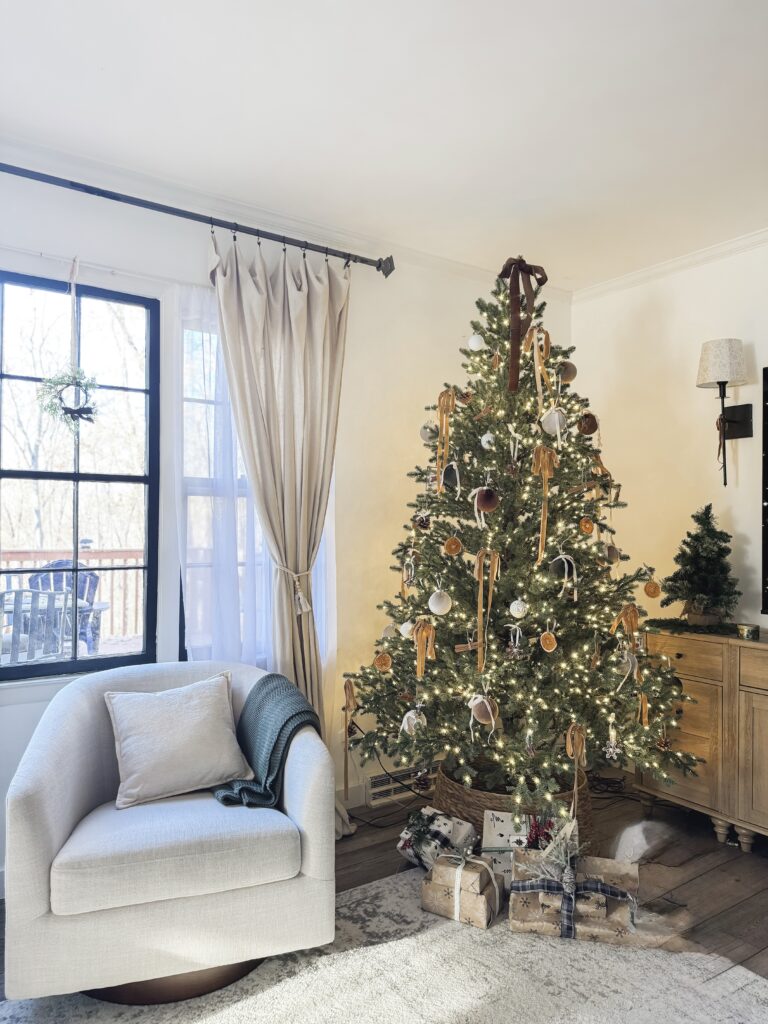 Festive decorated Christmas tree with ornaments and gift boxes, cozy living room with armchair and window, holiday decor and warm lighting, perfect for Christmas celebration and family gatherings.