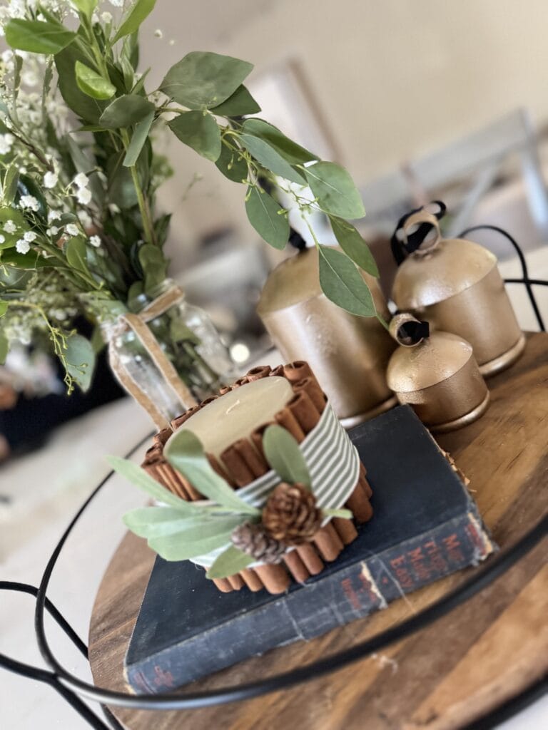 Rustic fall centerpiece with candles, greenery, and pinecones on vintage book for cozy autumn home decor, perfect for Thanksgiving or seasonal gatherings.