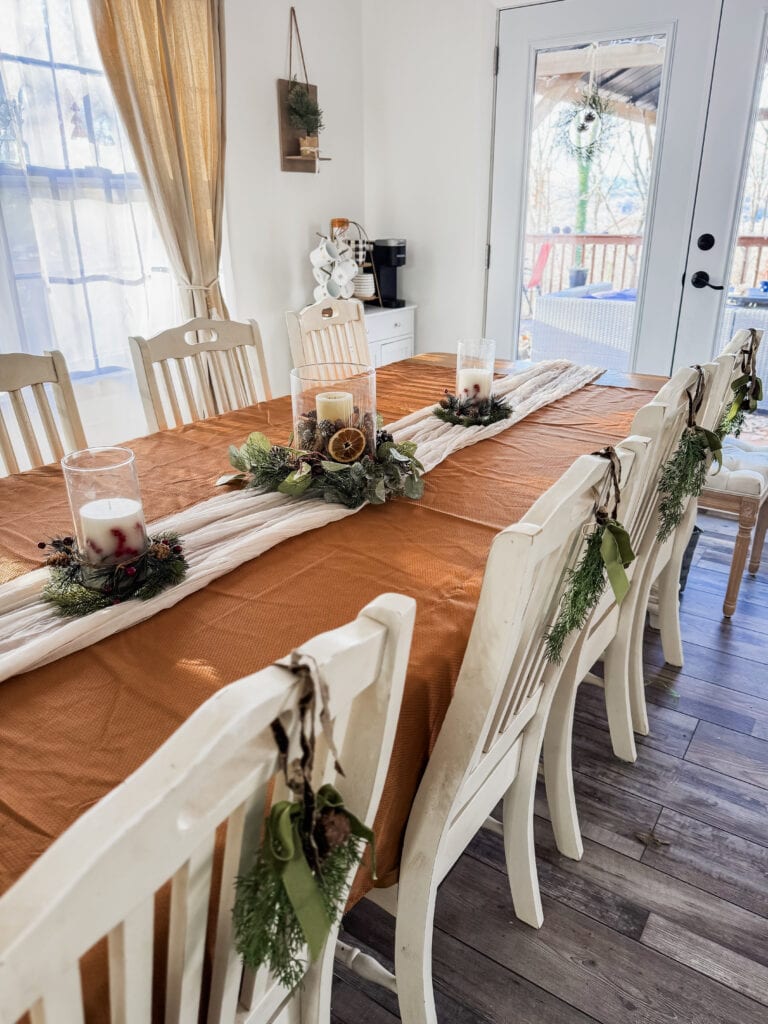 Festive holiday dining table with candles, greenery, and rustic decor, perfect for a Christmas or winter celebration.