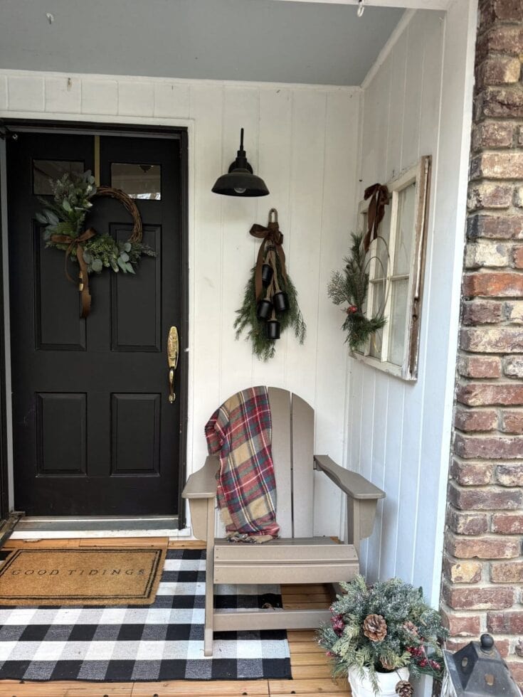 Cozy holiday front porch decorated with wreath, greenery, and plaid throw, featuring a welcome mat and seasonal decor for festive curb appeal.