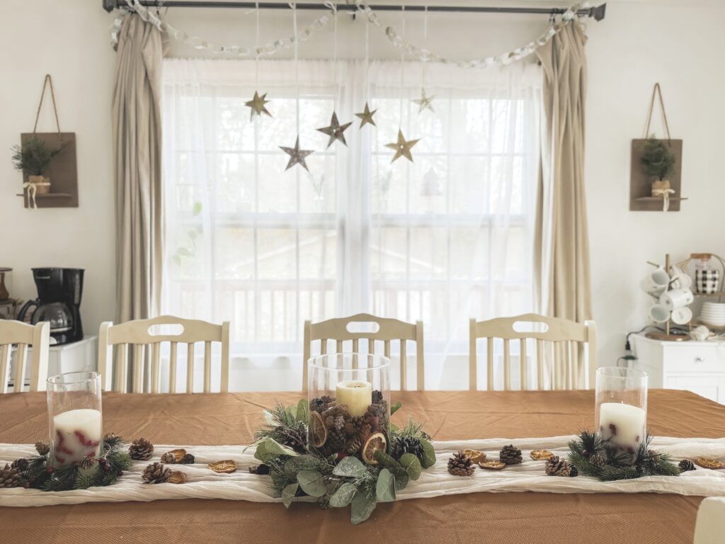 Festive holiday table setting with pinecones, greenery, candles, and dried orange slices, perfect for Christmas dinner or seasonal gatherings.