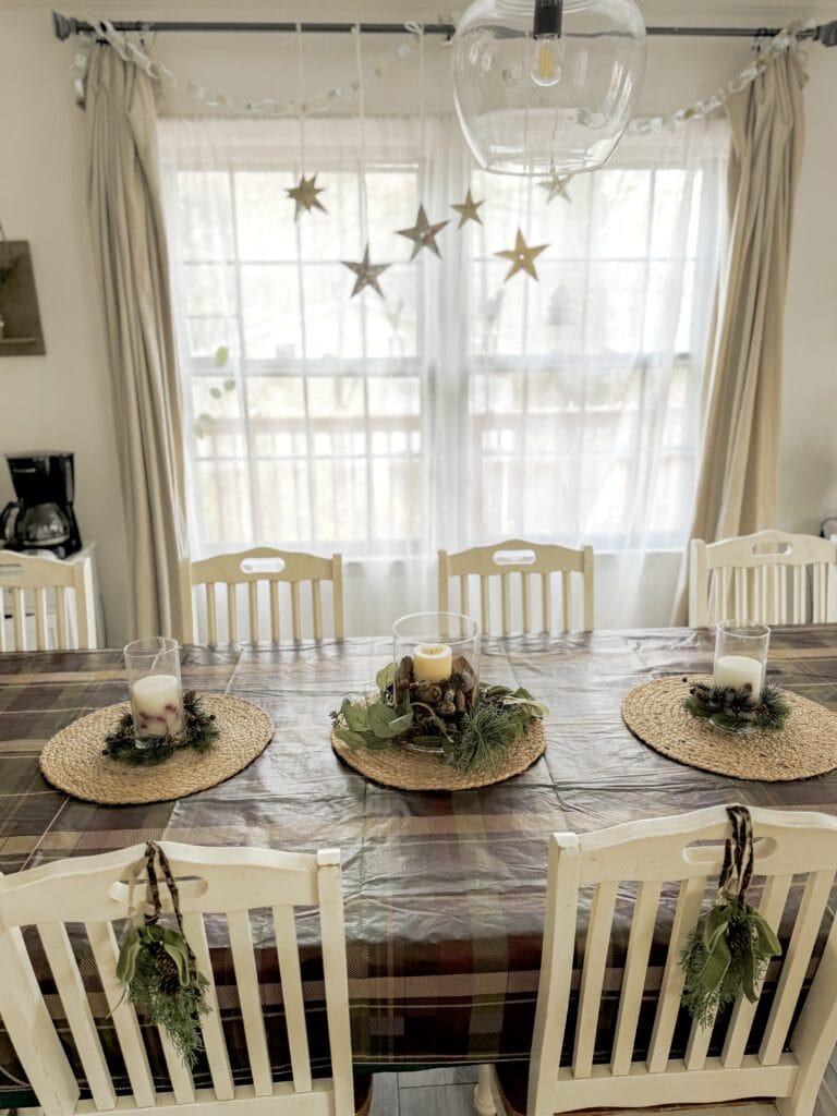 A cozy dining table decorated for a holiday or special occasion with candles, greenery, and natural accents, perfect for festive gatherings or family celebrations.