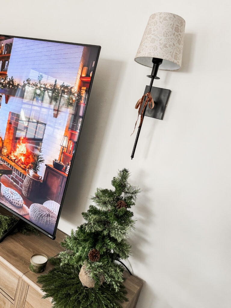 Festive Christmas scene with a small decorated pine tree and a cozy fireplace on a TV screen, highlighting holiday decor ideas and home decor inspiration.