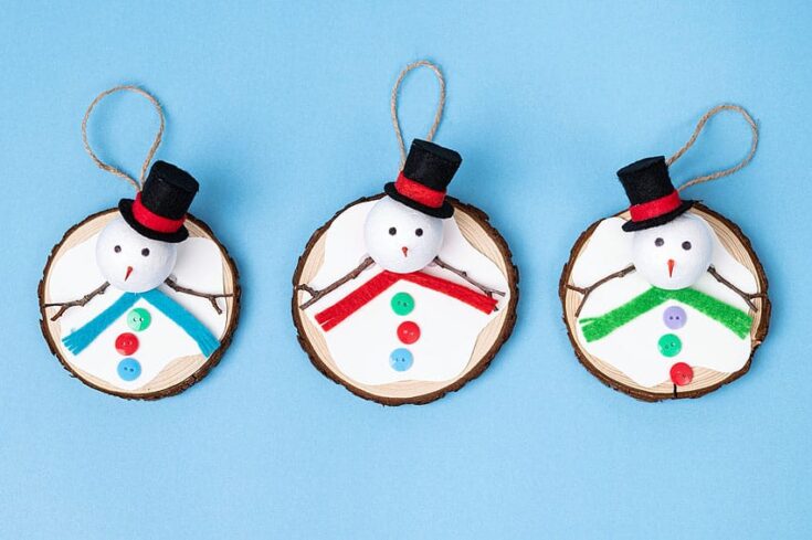 Adorable snowman ornaments made from wood slices, featuring buttons, colorful scarves, and top hats, perfect for holiday decorations and winter crafts.