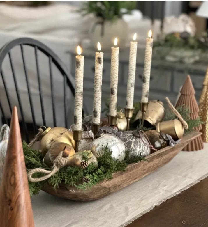 Rustic Christmas centerpiece with gold and silver ornaments, birch candles, greenery, and festive decor for holiday table decoration.