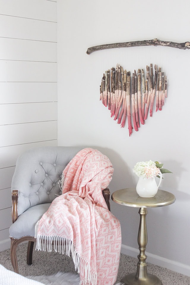 A charming corner with a vintage armchair, soft pink throw, and elegant vase with flowers, creating a warm and inviting atmosphere perfect for relaxation.