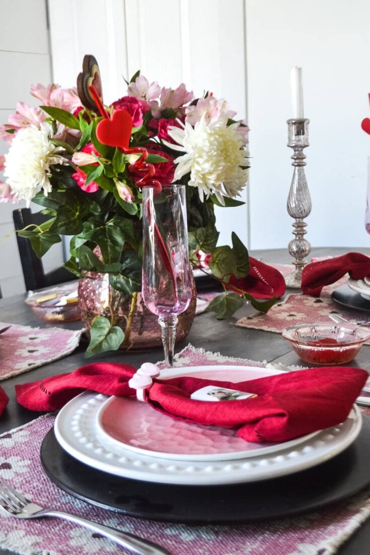 A beautiful Valentine's Day table centerpiece featuring pink and white flowers, candles, and elegant tableware for romantic celebrations.