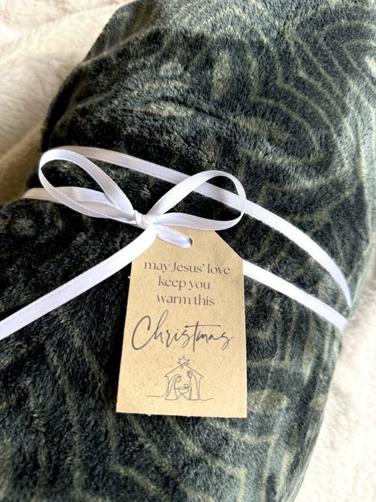 Soft, dark green velvet blanket with a white satin ribbon and a heartfelt holiday message tag. Perfect for Christmas warmth and comfort.