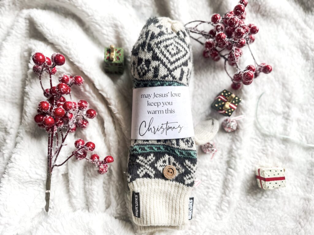 Festive Christmas-themed wool sock with a heartfelt message, surrounded by red frosted berries and miniature wrapped presents on soft white fabric. Perfect for holiday warmth and gift-giving.