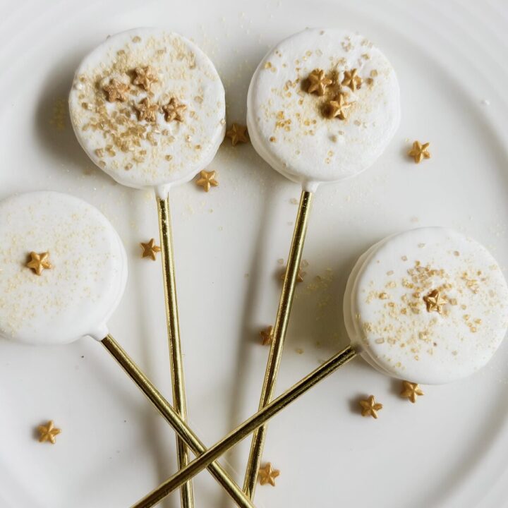 Delicious white cake pops decorated with gold star sprinkles and elegant gold sticks, perfect for weddings, parties, or special occasions.