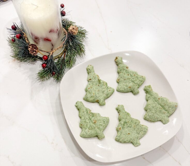 quesadillas shaped like Christmas trees on white dish with holiday candle decoration, perfect for Christmas finger foods and festive snacks.