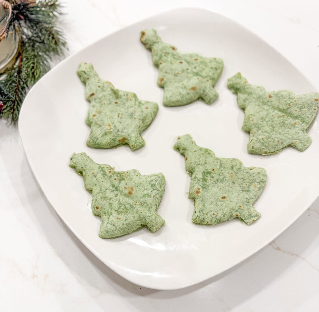 Delicious green Christmas tree cookies on a white platter, perfect for holiday celebrations and festive baking.