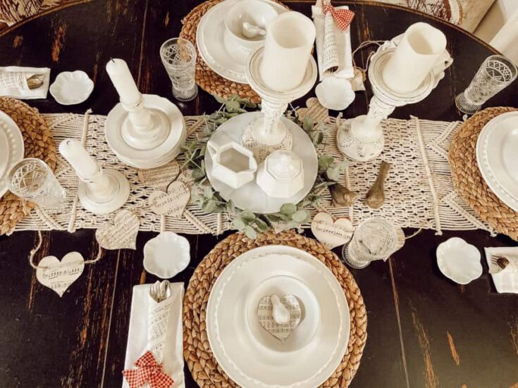 Charming rustic table setting with white candles, heart-shaped accents, and woven placemats for romantic dinners or special gatherings.