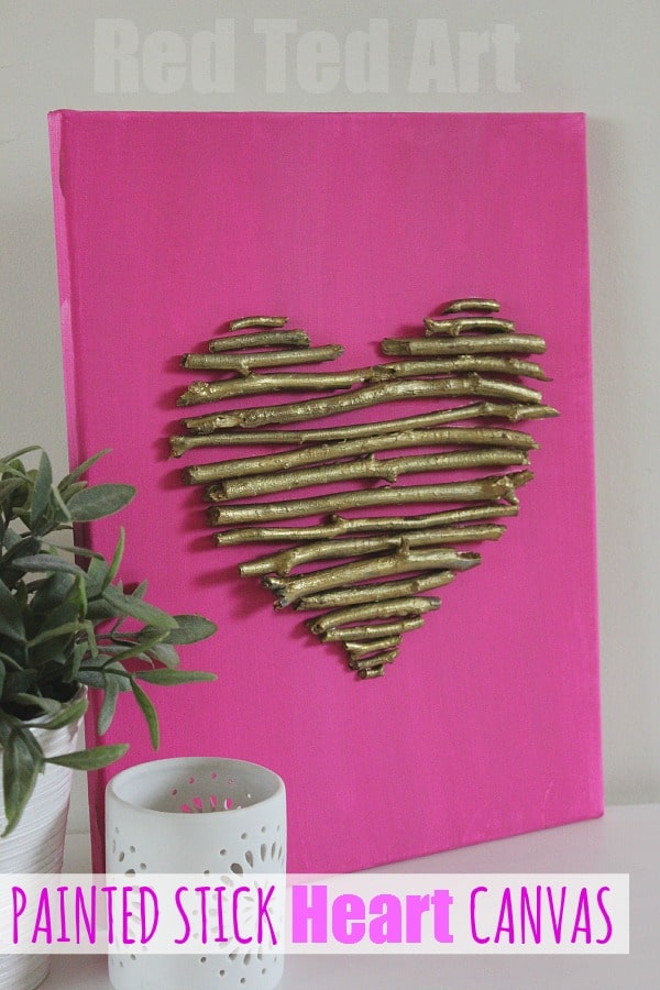 Bright pink canvas with gold-painted stick heart, perfect for romantic home decor and wall art. Unique DIY painted stick heart canvas, ideal for gift-giving or personal art projects.
