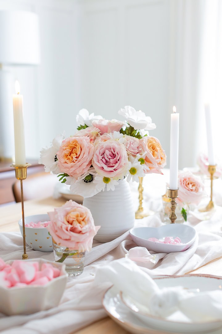 Beautiful pastel roses and daisies centerpiece with candles for romantic dining and wedding décor.