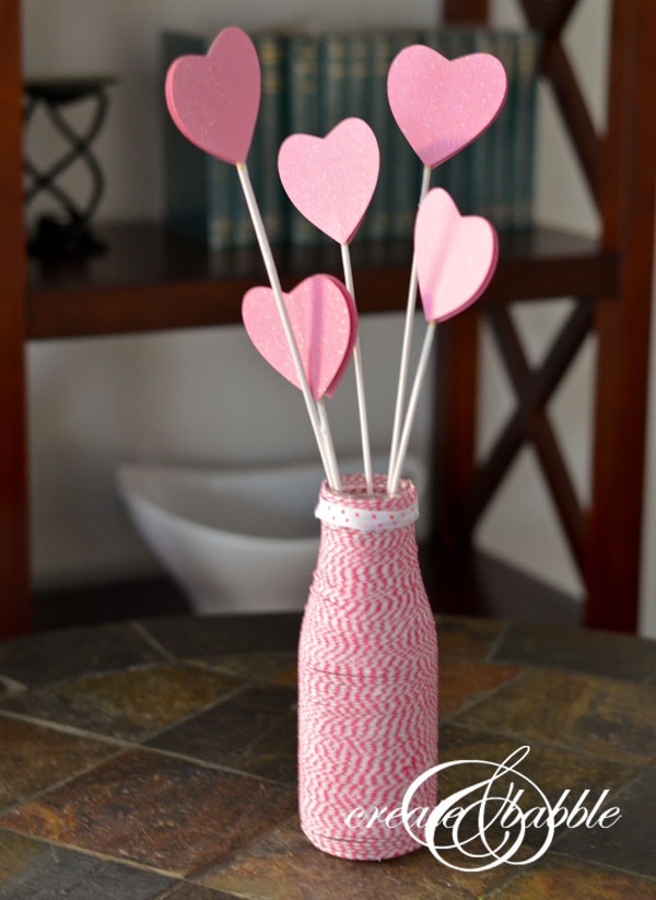 Pink paper heart picks in a yarn-wrapped vase for romantic or wedding decor, perfect for Valentine's Day, anniversary, or special occasions.