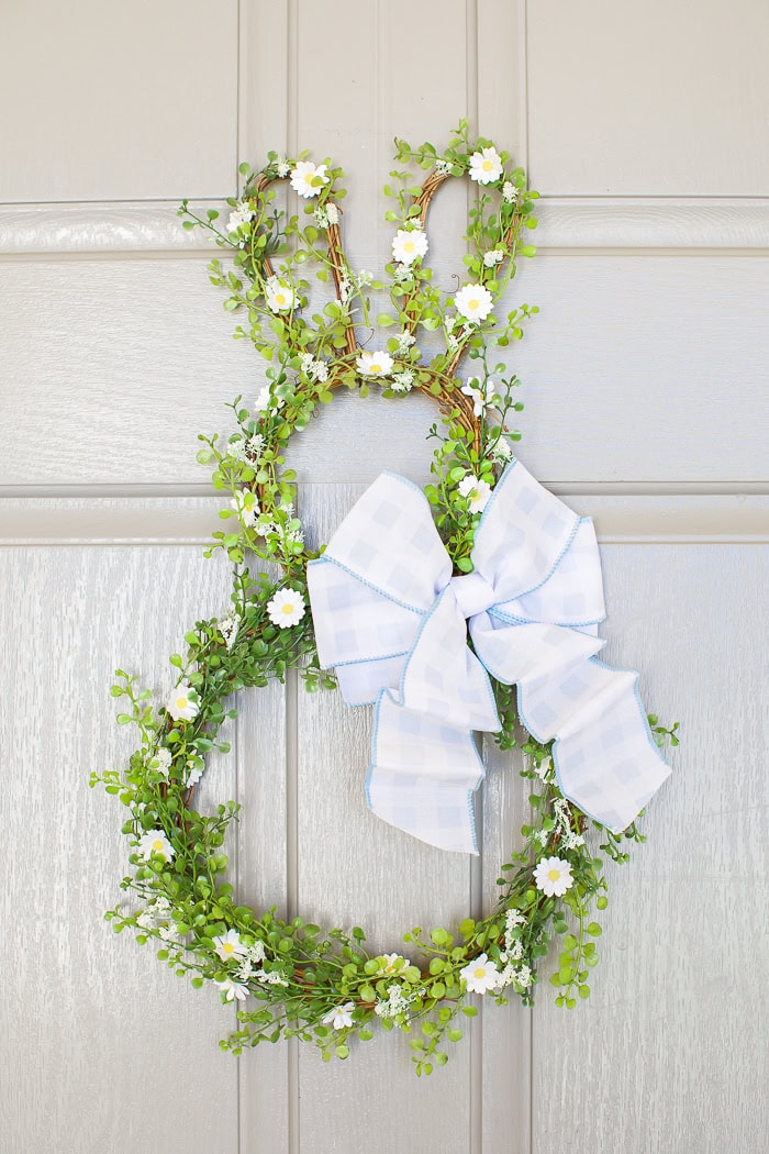 Beautiful spring floral wreath with greenery and white flowers, featuring a charming blue checkered bow. Perfect for spring decor and home decoration.