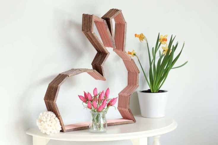 Decorative wooden heart wall art with pink and brown tones, complemented by vibrant flowers in a modern home decor setting.
