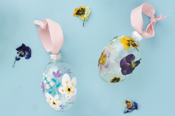 Colorful hand-painted glass ornaments featuring pressed flower designs and pink ribbons, perfect for home decor or gift-giving.