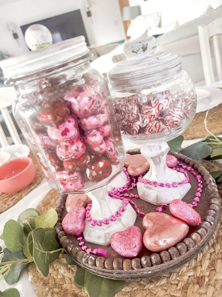 A charming arrangement of pink and red heart-shaped candies and wrapped chocolates displayed on a rustic tray, perfect for Valentine's Day or romantic celebrations.