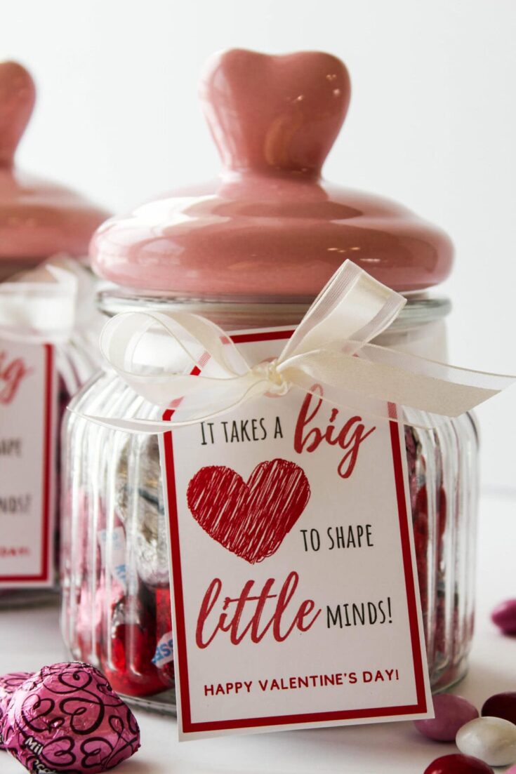 A decorative glass jar filled with sweet treats for Valentine's Day, featuring a charming pink lid and a heartfelt message for loved ones. Perfect for expressing affection and love during special occasions.