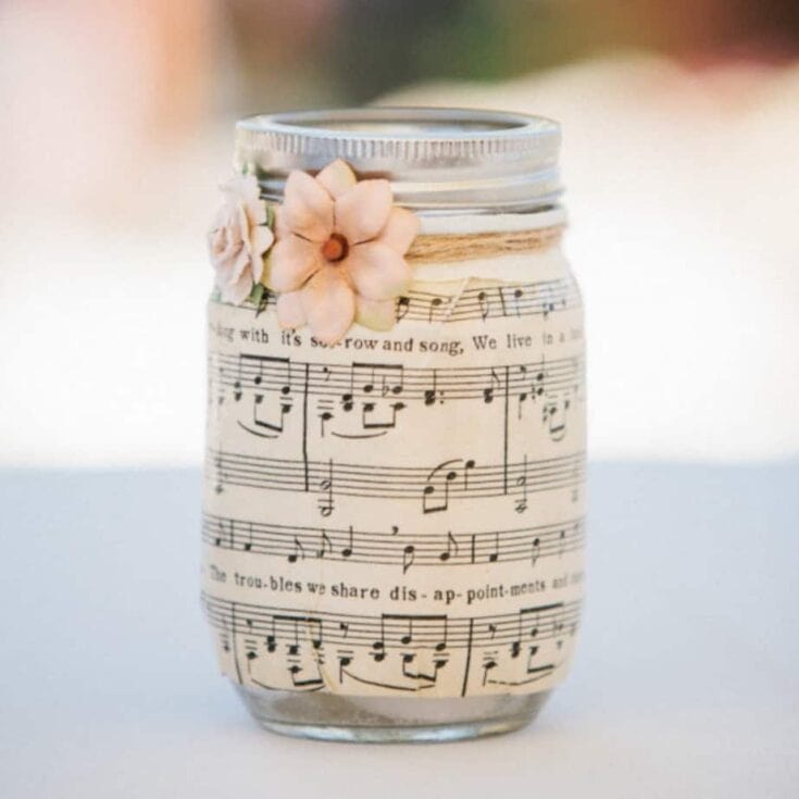 Decorative mason jar with sheet music and small pink flowers, perfect for musical or handmade gift ideas and home decor.