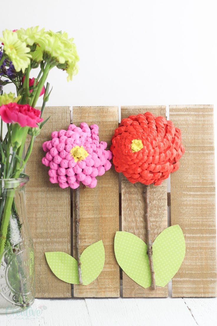 Colorful handmade paper flowers with green leaves, perfect for children's craft projects and decorating. Inspired by spring and nature themes for kids' art activities.