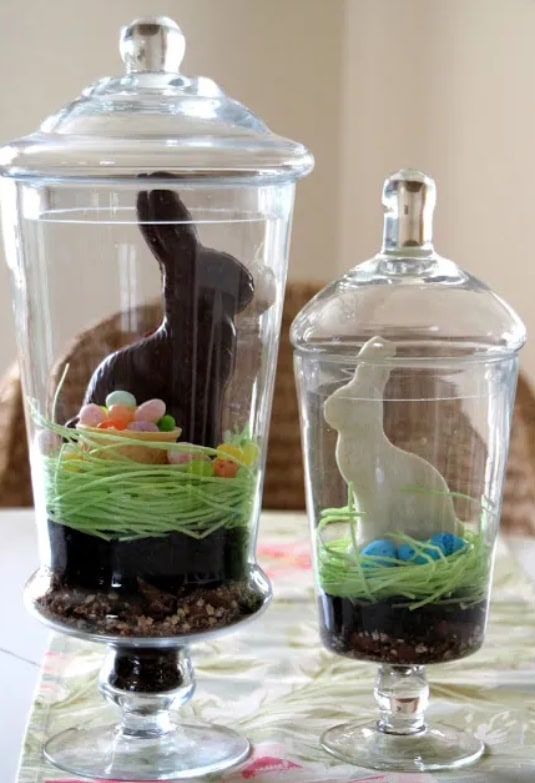 Elegant glass candy jars with bunny-shaped chocolate figures, colorful candy, and decorative grass, perfect for Easter or spring celebration decor.