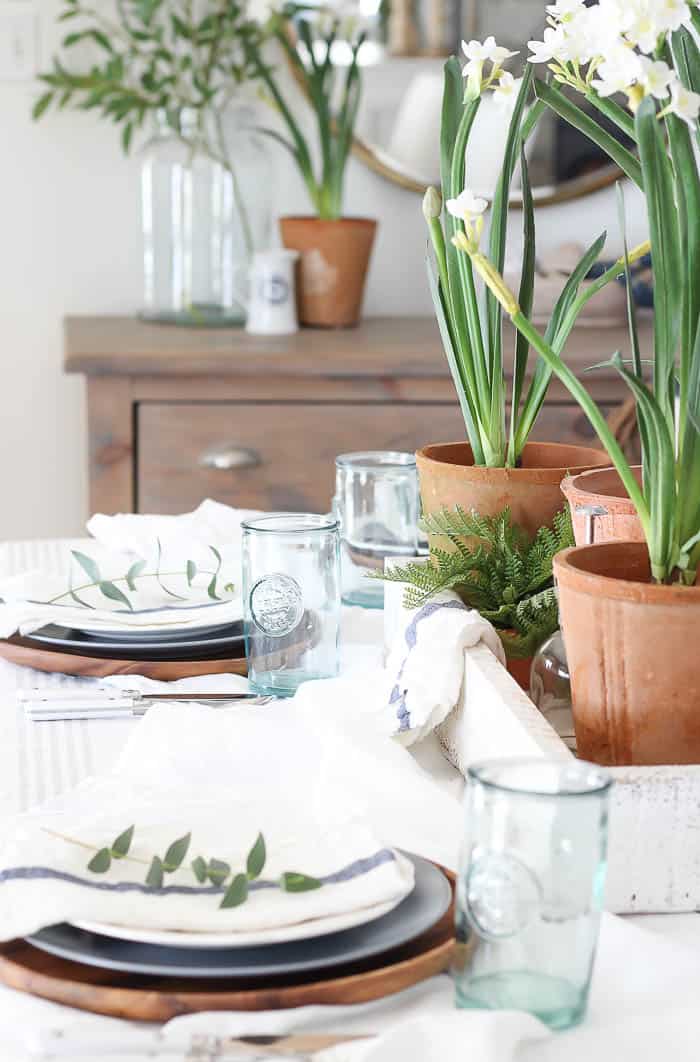 Elegant table with potted white flowers, glassware, and natural decor for a stylish home dining experience.
