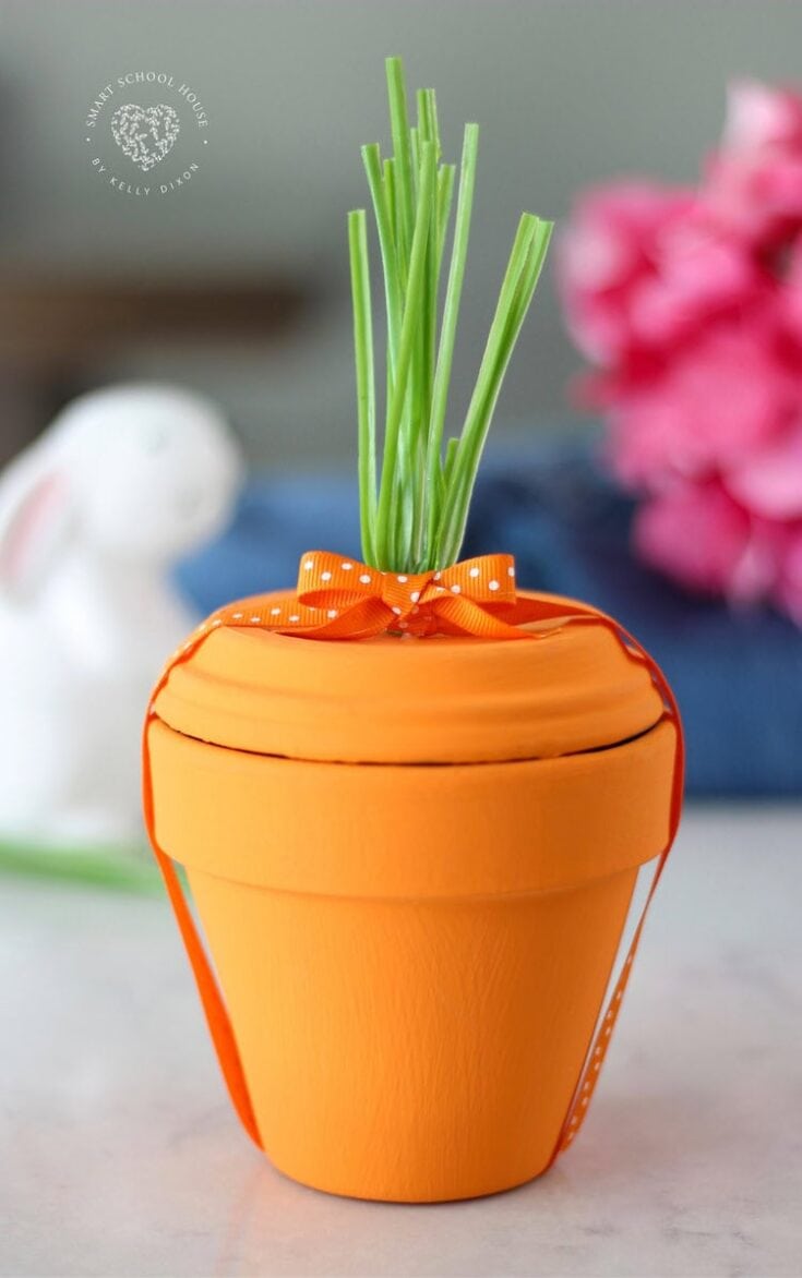 Bright orange planter with green plant and decorative bow, perfect for Mother's Day and spring-themed home decor, gift for women who love gardening and floral arrangements.