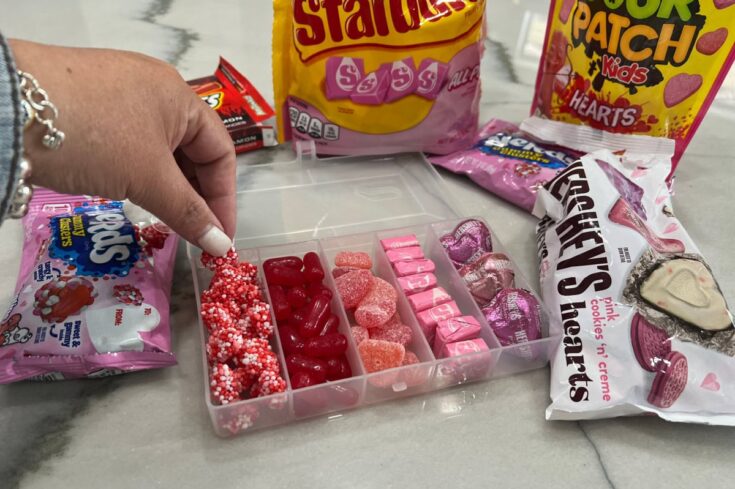 A variety of colorful Valentine's Day candies and gummies arranged on a marble surface, perfect for making personalized candy mixes or gift boxes.