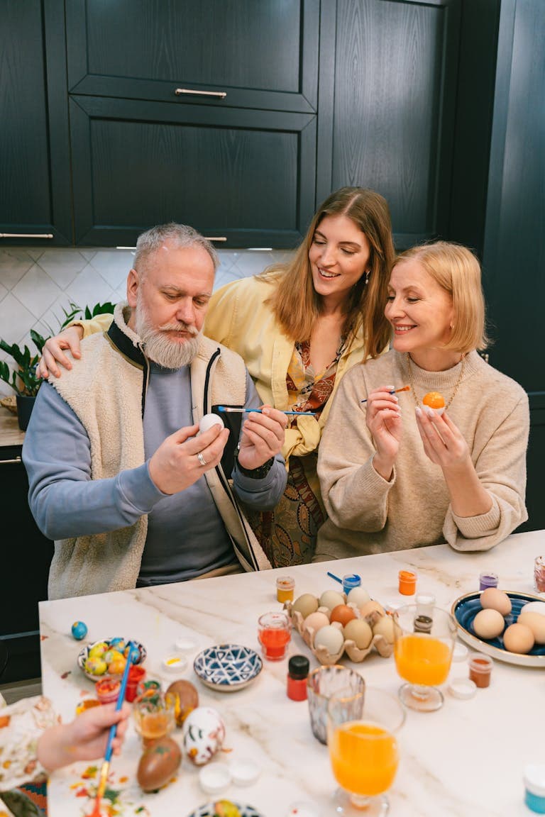 Beautiful family enjoying Easter egg decorating with vibrant dyes and creative designs in a cozy kitchen setting.