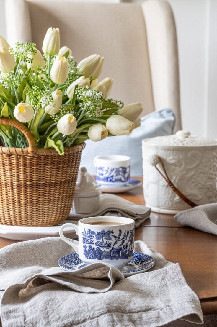 Elegant table setting with white tulips and vintage blue-and-white china for a cozy, garden-inspired decor.