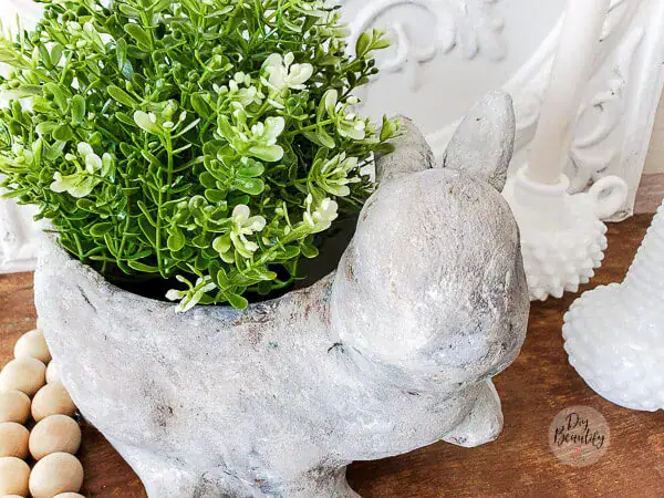 A charming bunny-shaped concrete planter filled with lush green plants, perfect for adding a whimsical touch to your home or garden decor.