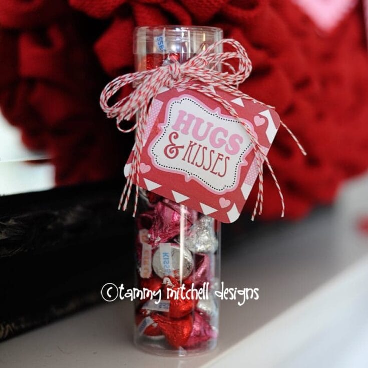 A cute Valentine's Day candy jar decorated with a “Hugs & Kisses” tag, red and white twine, filled with chocolates and candies, perfect for gifting or romantic celebration.
