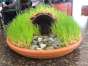 Beautiful miniature water fountain with lush grass, decorative rocks, and a ceramic pipe feature, perfect for adding tranquility to any space.