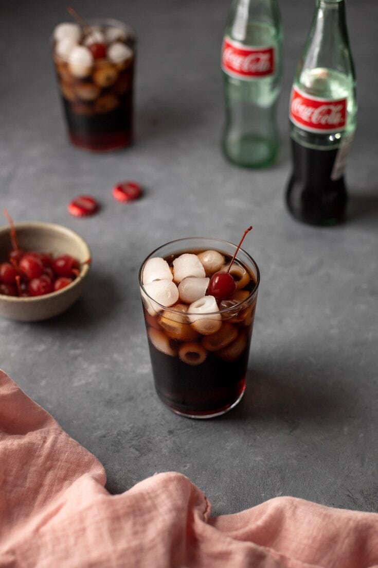 Refreshing vintage soda float featuring ice cream, marshmallows, maraschino cherries, and cola in a glass.