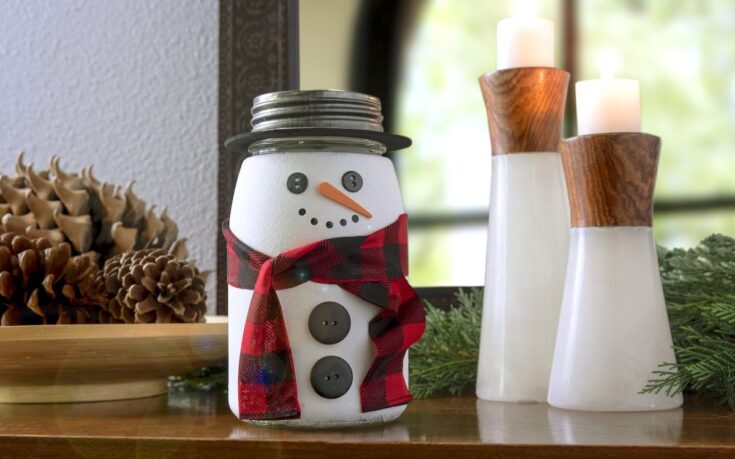 Cute snowman jar with button eyes, carrot nose, and red plaid scarf, perfect for Christmas holiday decorations.