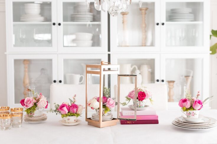 Beautiful pink roses in floral arrangements on a white table with gold and clear glass accents, perfect for weddings or celebrations.