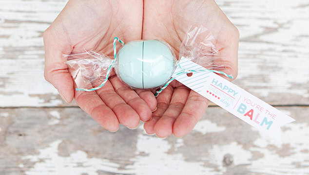 An adorable pastel blue bath bomb wrapped in clear plastic with a "Happy you’re the balm" tag, perfect for thoughtful gifts and self-care.