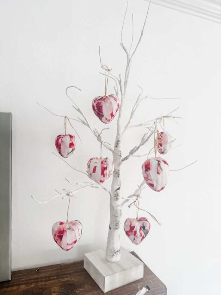 Decorative white tree with hanging heart-shaped ornaments in pink and red, perfect for Valentine's Day or romantic decor.