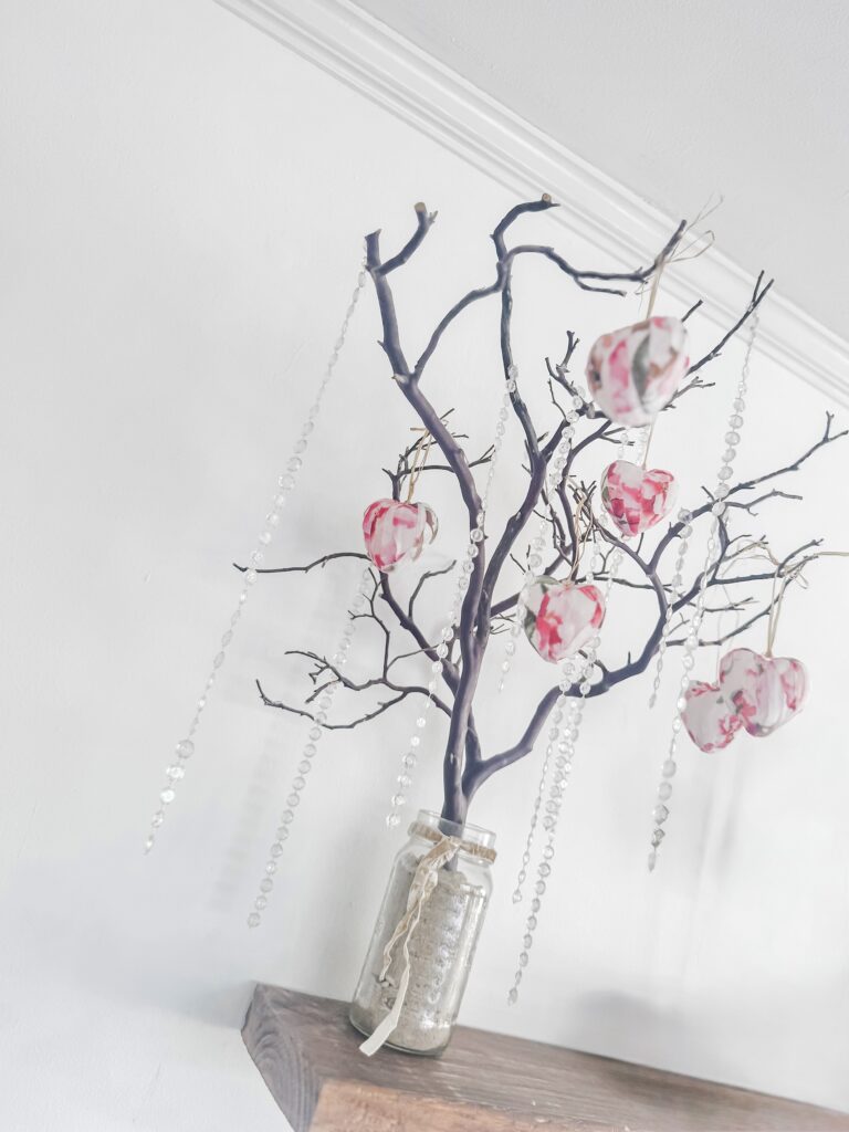 Decorative branch with hanging paper hearts and beads for Valentine's Day or romantic decor.