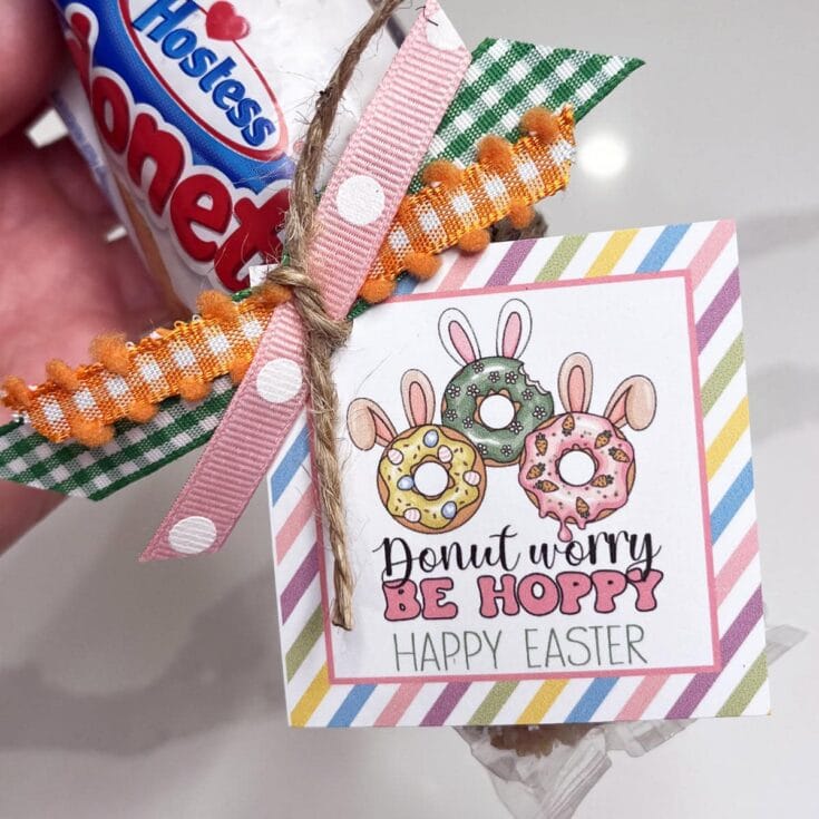 A colorful Easter card featuring adorable donut illustrations with bunny ears, cheerful pastel stripes, and the playful message "Donut Worry Be Hoppy" for celebrating spring and Easter.