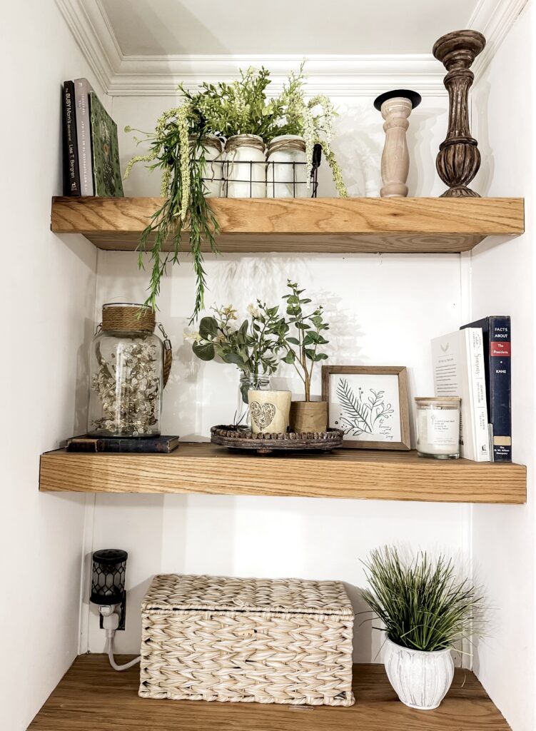 Aesthetic wall shelves decorated with potted plants, candles, and books, creating a warm and inviting home decor display. Perfect for enhancing interior style and ambiance.