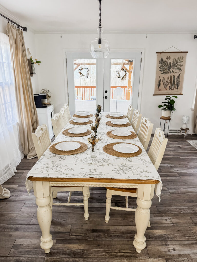 Bright and inviting dining room setup with a rustic wooden table, white chairs, and natural light, perfect for family gatherings and intimate dinners.