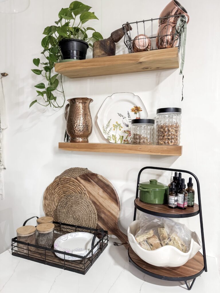 Aesthetic kitchen shelf display featuring potted plants, copper and ceramic containers, and organized jars for a stylish and functional kitchen setup.