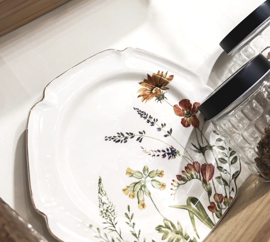A beautifully designed ceramic plate featuring colorful floral patterns, accompanied by glass jars, perfect for home decor or serving dishes.