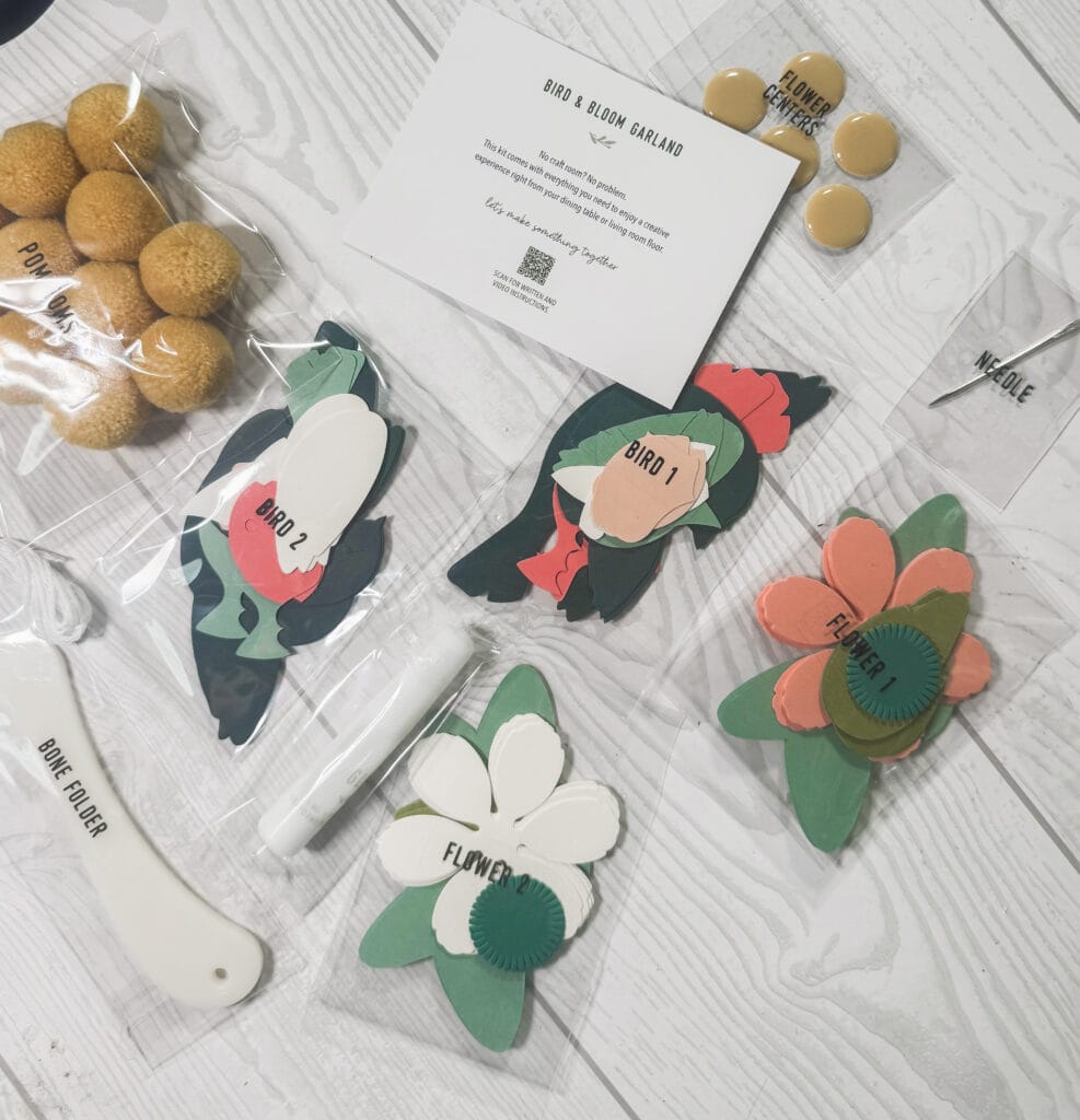 Brightly colored paper flowers, bird cutouts, and craft tools for creating personalized floral and bird-themed decorations.