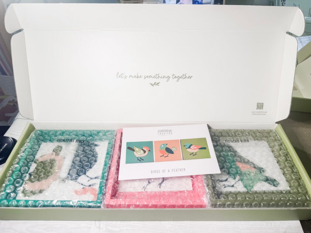 A beautifully organized kit featuring bird-themed patterns, colorful papers, and tools, perfect for crafting and creating personalized textile art.